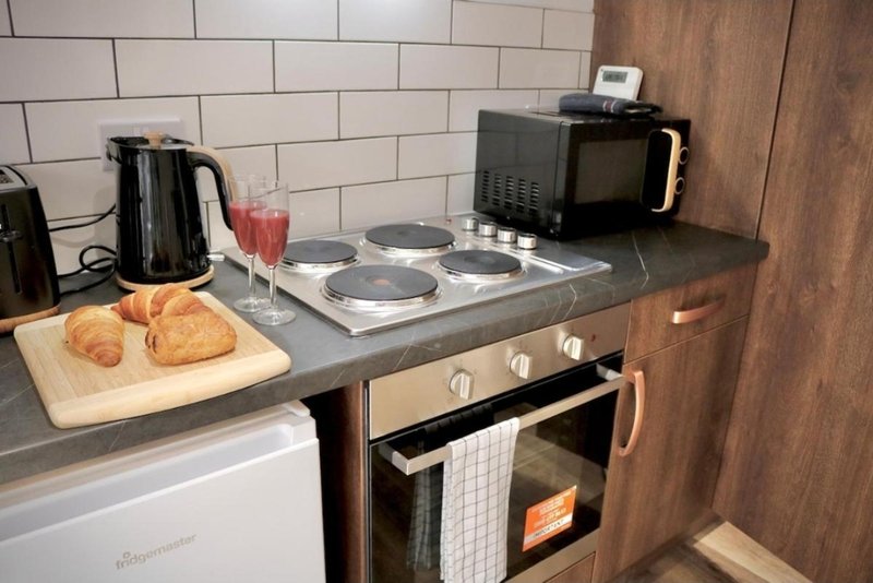Compact kitchen with electric stove, kettle, toaster, and fresh croissants on counter