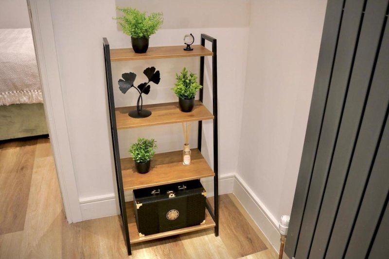 Wooden and black metal shelving unit with potted plants, decorative items and storage drawer