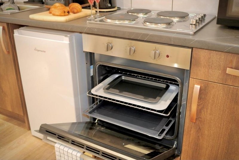 Modern kitchen with built-in oven, stovetop, oranges on counter and stainless steel cookware