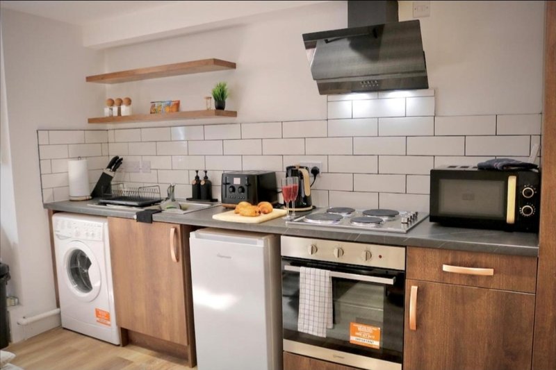 Modern kitchen with white subway tile backsplash, wooden cabinets, stainless steel appliances and shelving