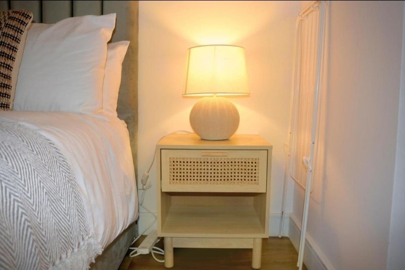 Bedroom corner with white bedside table, round lamp, and patterned pillows