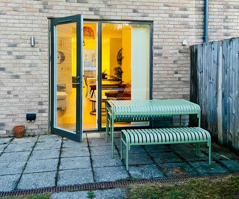 Brick patio with green bench seating and glass sliding doors to interior room
