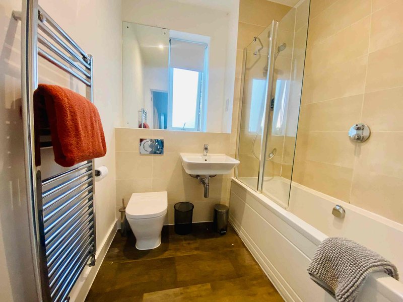 Modern bathroom with toilet, sink, mirror, towel rail and shower bath enclosure