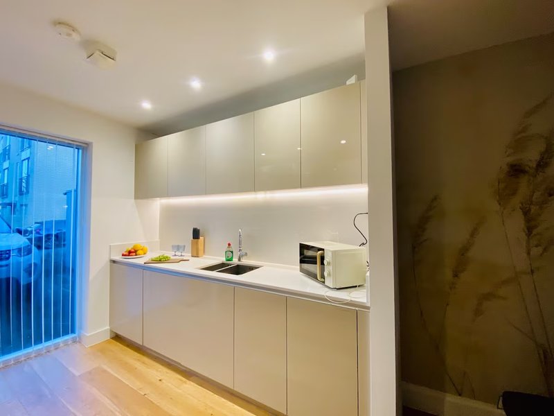 Modern kitchen with cream cabinets, white countertop, integrated appliances and wooden flooring