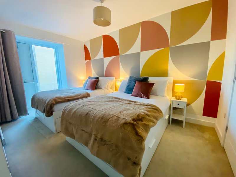 Modern bedroom with double bed, colorful geometric wall art, and warm lighting