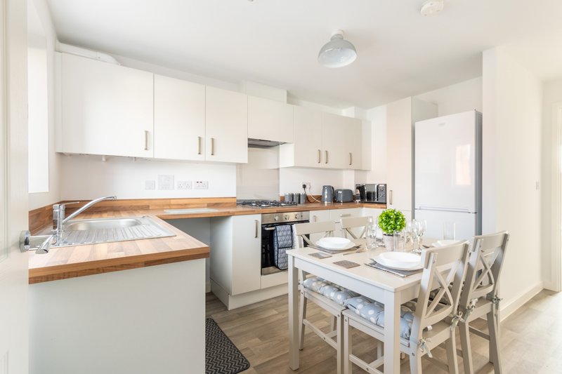 Modern kitchen with white cabinetry, wooden countertop, dining table and chairs