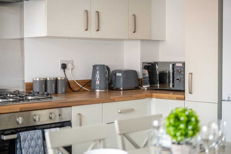 Modern kitchen with white cabinets, wooden countertop, and various appliances and kitchenware