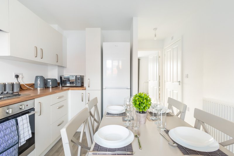 Modern kitchen-diner with white cabinetry, wooden worktops, dining table and chairs