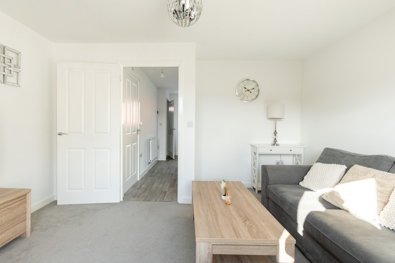 Bright bedroom with double bed, wooden coffee table, gray carpet and white wardrobe doors