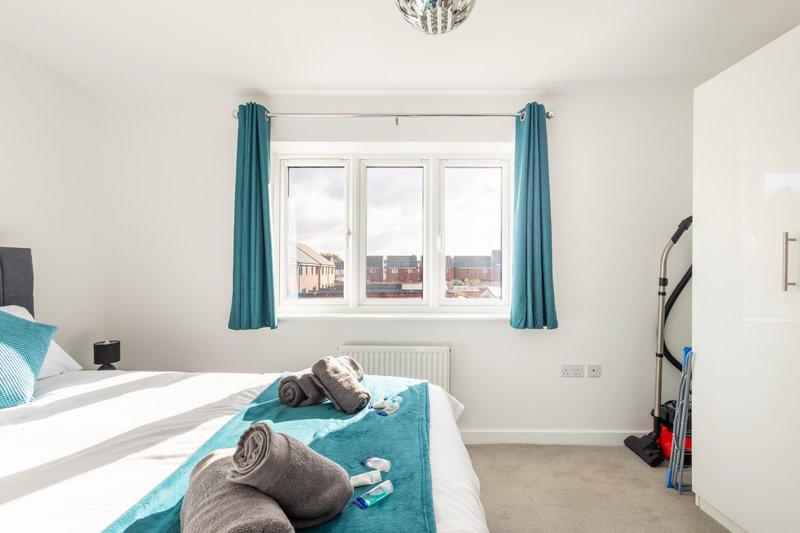 Bright bedroom with double bed, turquoise curtains, large window with city view