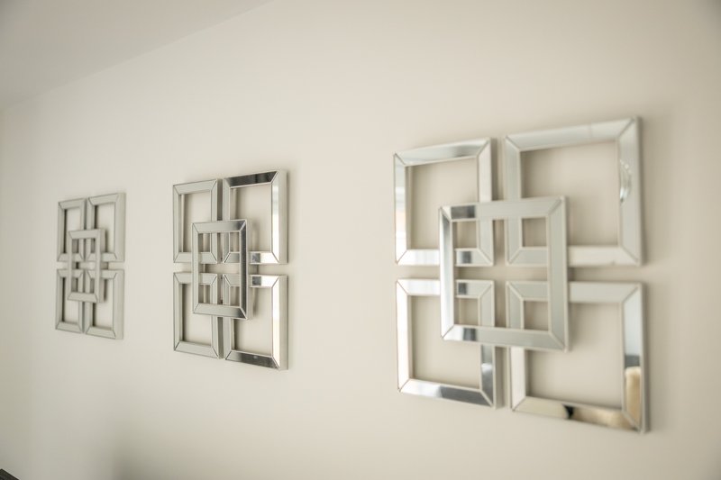 White wall with three geometric mirror decorations of varying sizes