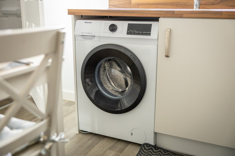 Modern laundry room with white front-loading washing machine and wooden counter