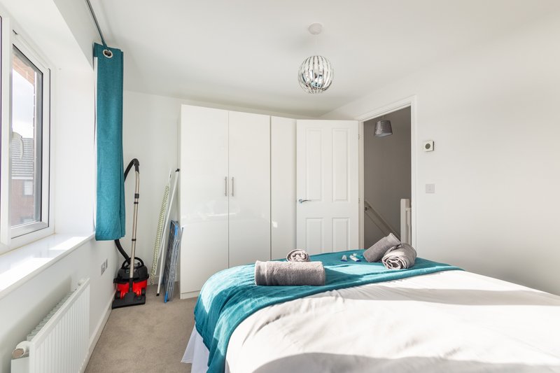 Modern bedroom with double bed, white built-in wardrobes, turquoise accents and pendant ceiling light