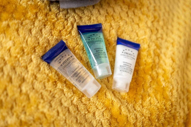 Three branded toiletry bottles arranged on a yellow textured towel