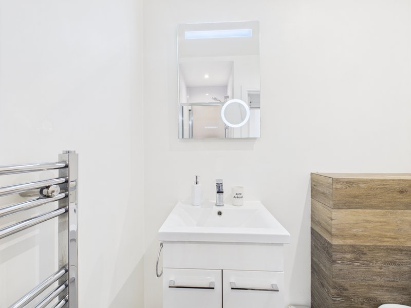 Modern bathroom with white sink, mirror cabinet, heated towel rail and wooden panelling