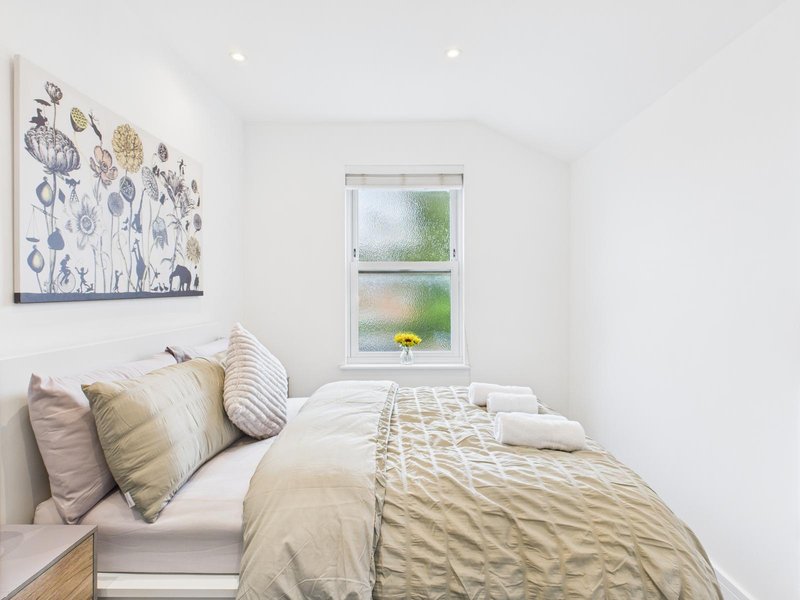 Bright bedroom with double bed, patterned bedding, decorative pillows and framed wall art
