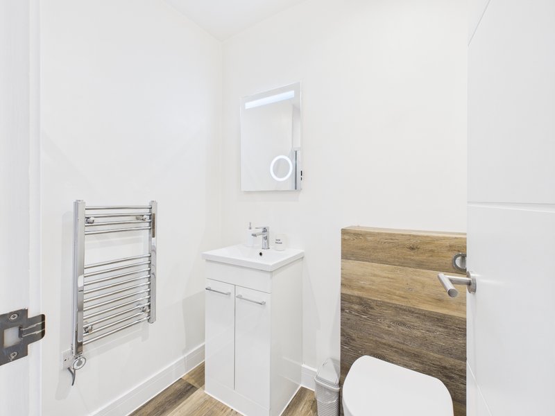 Modern bathroom with white vanity, mirror cabinet, heated towel rail and wooden toilet seat