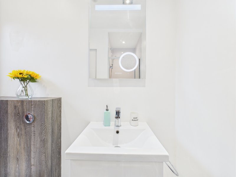 Modern bathroom with white sink, mirror, and wooden vanity with yellow flowers