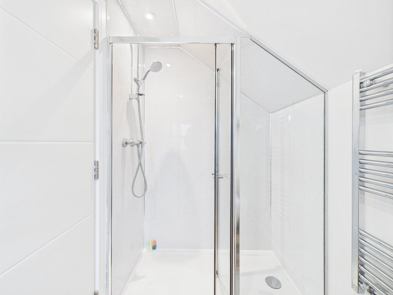 Modern bathroom with enclosed shower cubicle, white tiles, and heated towel rail