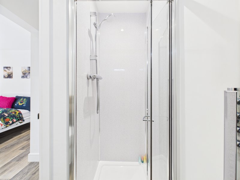 Modern bathroom with glass shower enclosure, white tiled walls and chrome fixtures