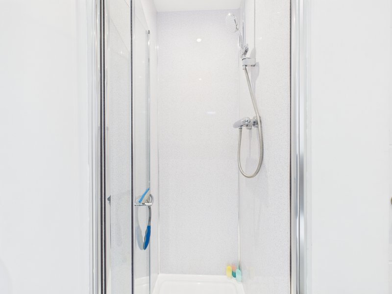 Bathroom shower enclosure with chrome fixtures and white tiled walls