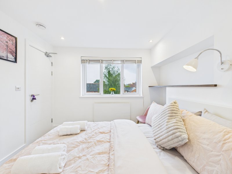 Modern bedroom with double bed, striped pillows, window with garden view, and arc lamp