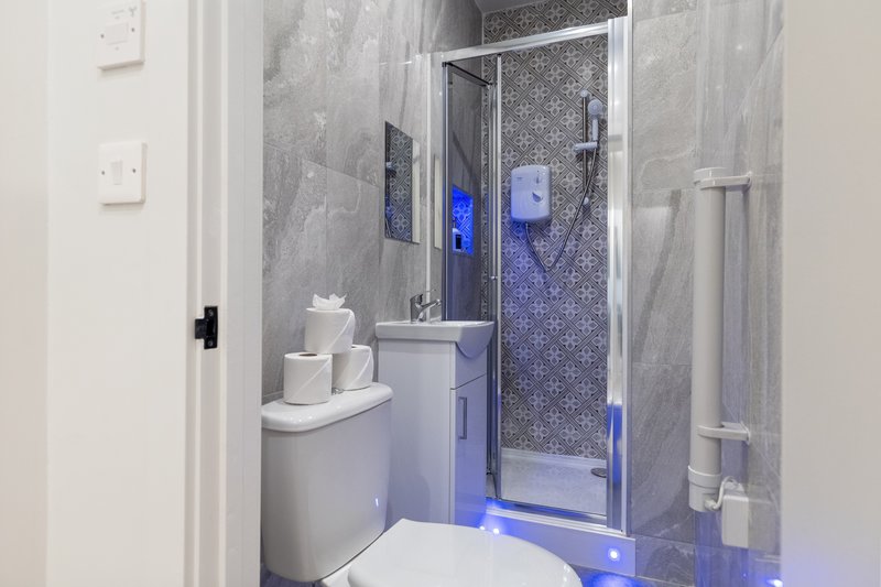 Modern bathroom with toilet, sink, shower enclosure and blue accent lighting