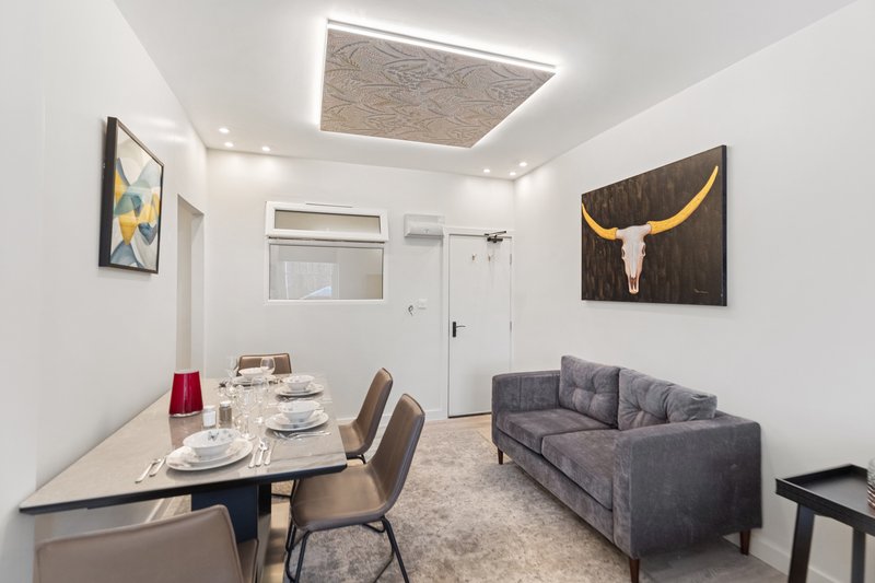 Modern open-plan living and dining area with gray sofa, dining table, and contemporary wall art