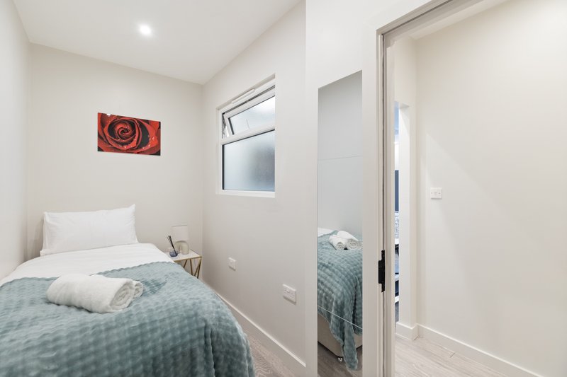 Compact bedroom with single bed, white pillow, blue bedding and red wall art