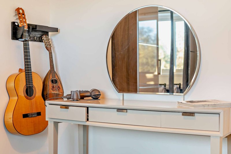 Bedroom dressing table with guitar, mandolin, round mirror and window view