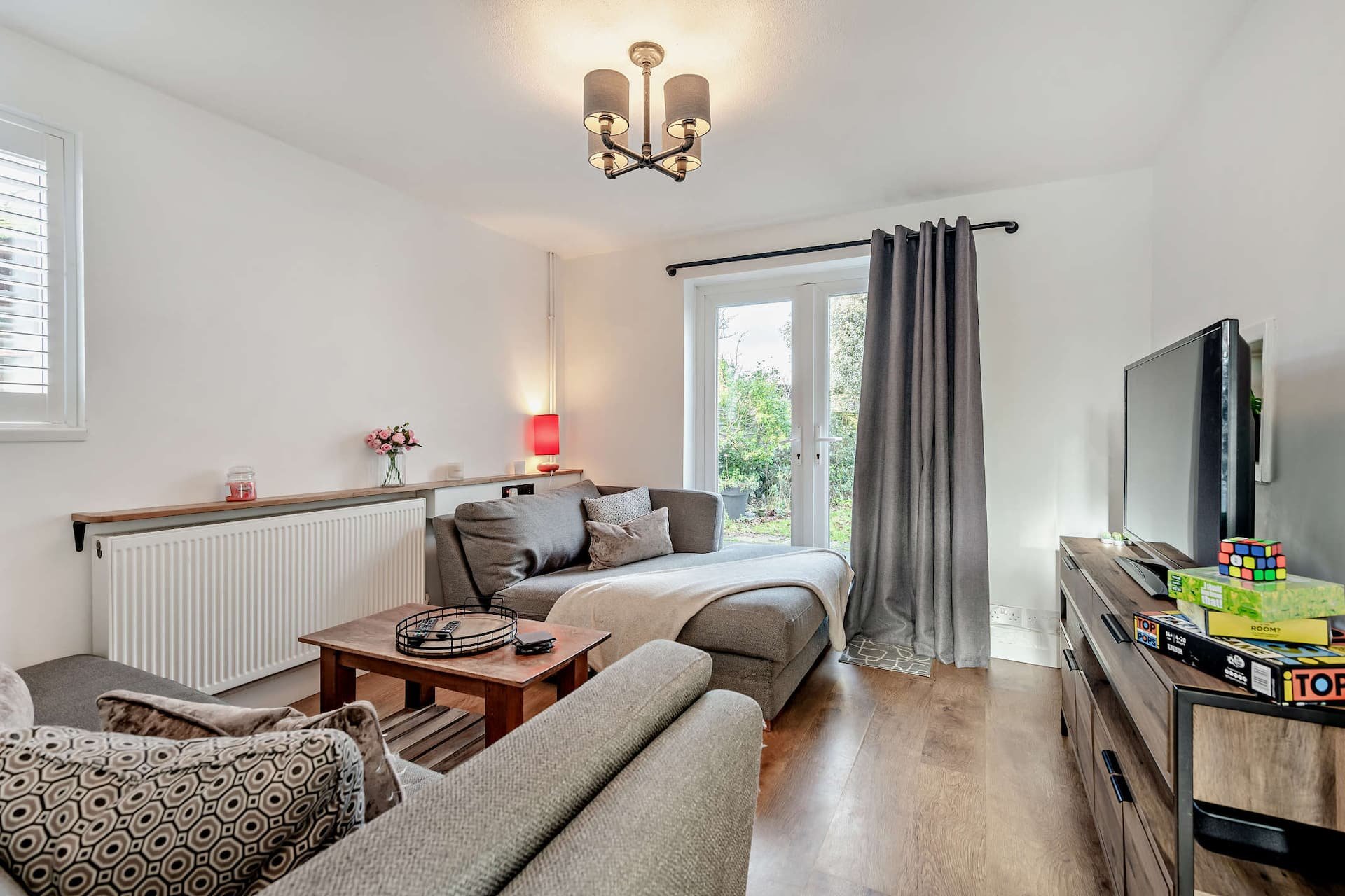 Bright living room with sofas, coffee table, TV, and patio doors to garden