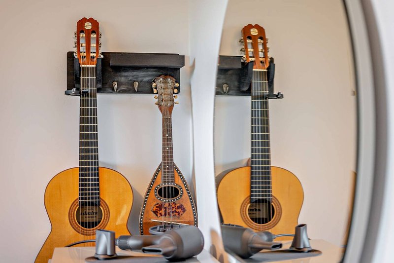 Two acoustic guitars and a mandolin displayed on wall mounts with headphones