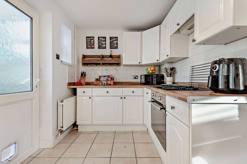 Modern kitchen with white cabinets, wooden worktops, stainless steel appliances and tiled floor