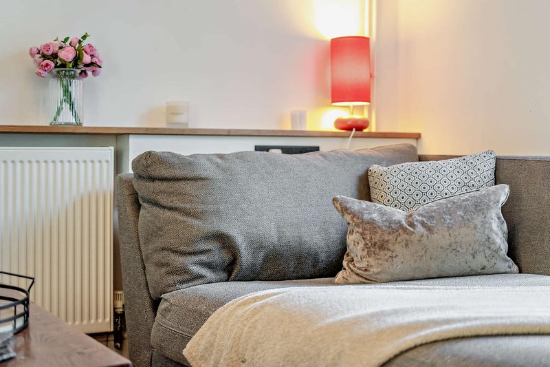 Bedroom with upholstered headboard, decorative pillows, fresh flowers, and bedside lamp