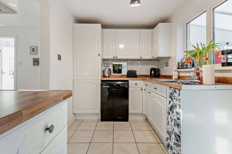 Modern kitchen with white cabinets, wooden countertop, black oven and tiled flooring