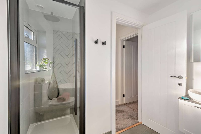 Modern bathroom with walk-in shower, herringbone tile, and white vanity cabinetry