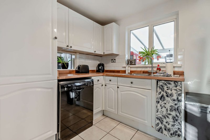 Modern kitchen with white cabinetry, black oven, wooden countertop and potted plants on windowsill