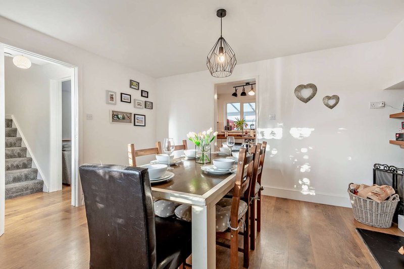 Open-plan dining room with wooden table, chairs, pendant light and staircase access