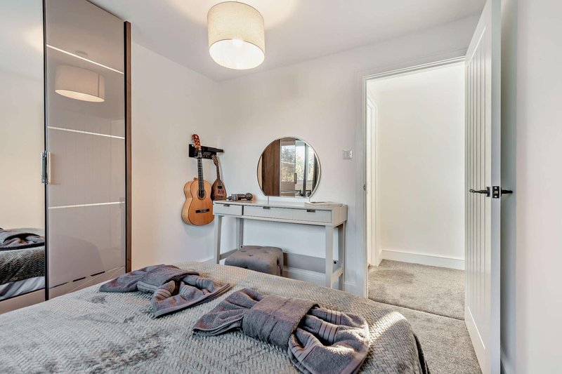 Bedroom with double bed, vanity desk, mirror, guitar, and en-suite door