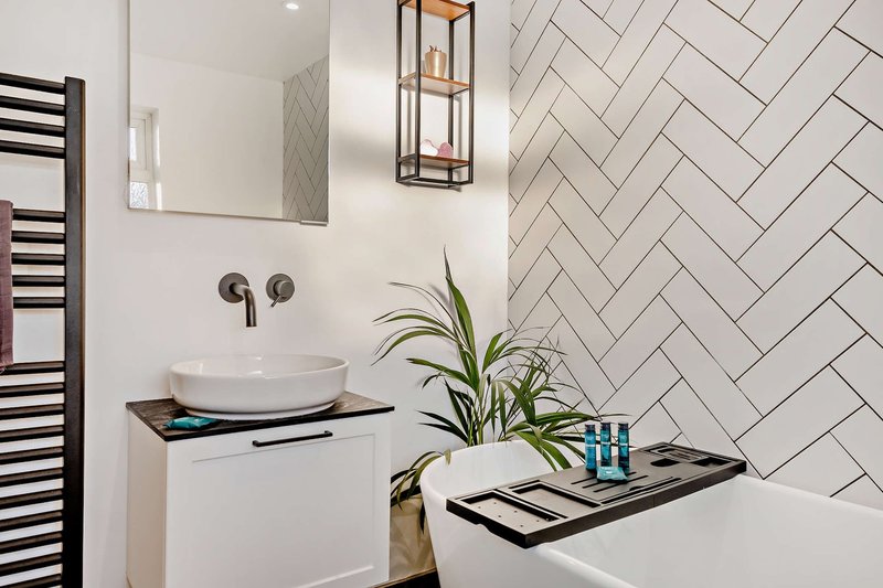 Modern bathroom with white subway tile, round vessel sink, mirror, and potted plant