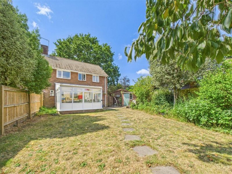Brick detached house with garden, wooden fencing, and outbuildings visible