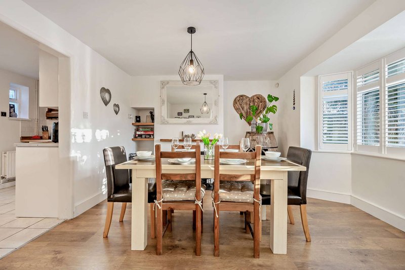 Modern dining room with wooden table, chairs, pendant light and open-plan kitchen view