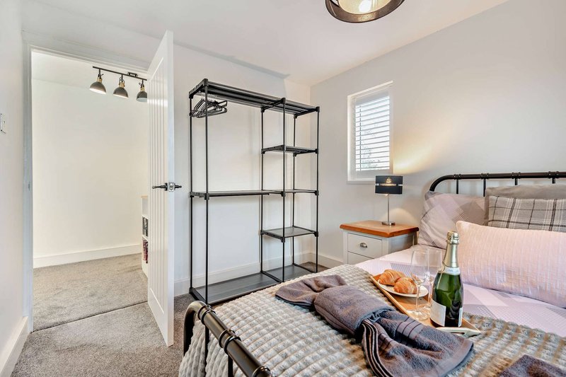 Bright bedroom with double bed, ensuite bathroom, black-framed shower enclosure, and wooden nightstand