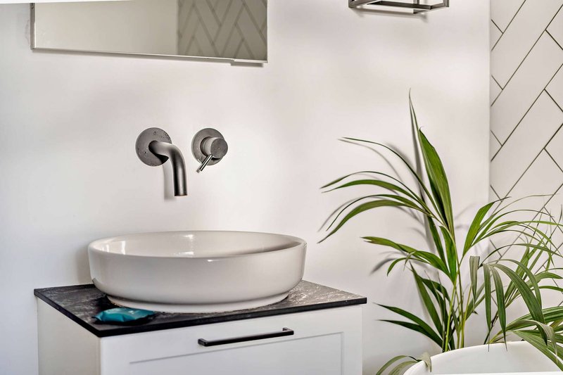 Modern bathroom sink with white basin, wall-mounted faucet and potted plant