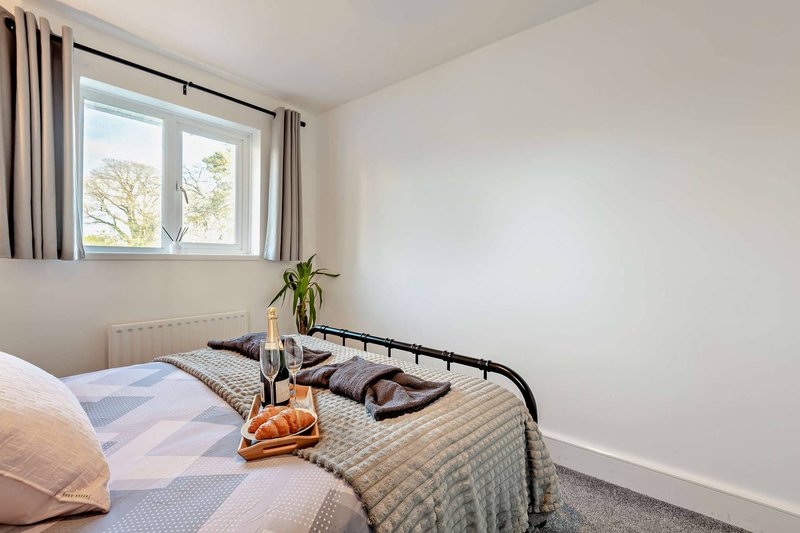 Bright bedroom with double bed, metal frame, window with curtains and potted plant