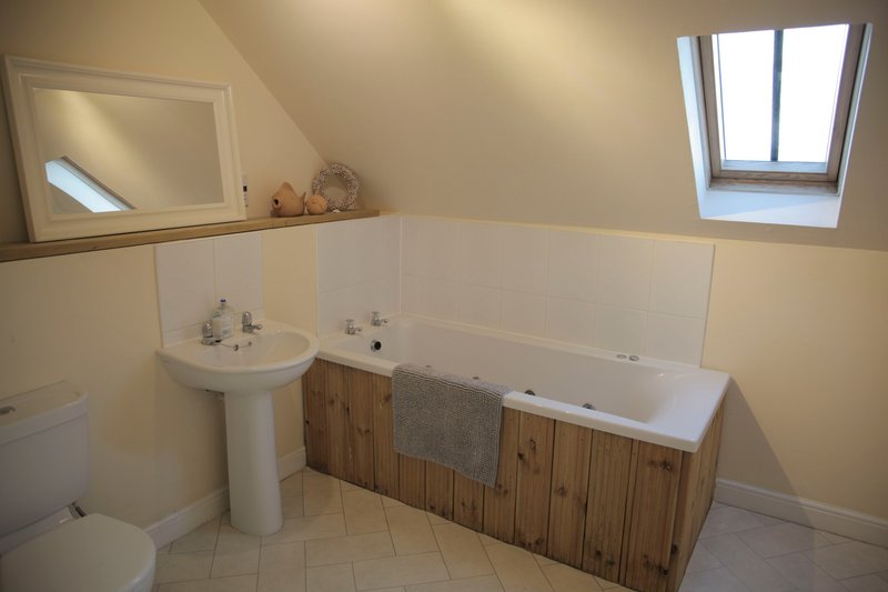 Attic bathroom with pedestal sink, bathtub, wooden paneling and skylight window