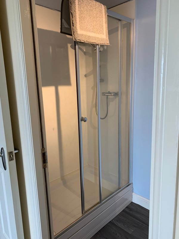 Bathroom with glass-enclosed shower cubicle, dark floor and towel rail