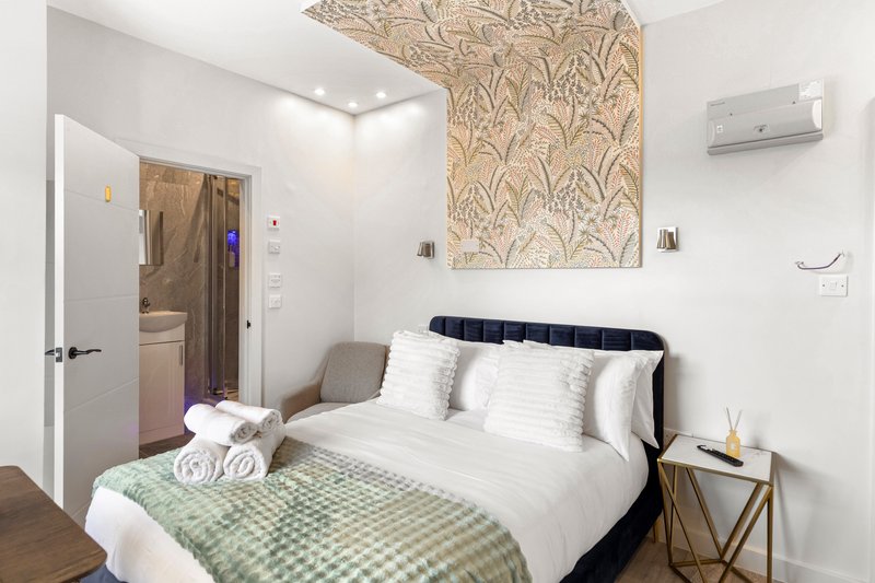 Modern bedroom with double bed, green gingham throw, white pillows and wooden bedside table