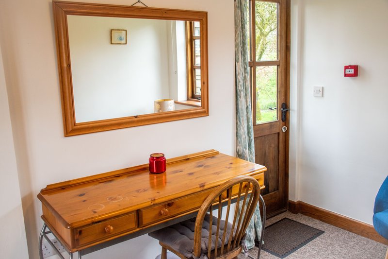 Wooden desk with chair and mirror, natural light from glass door and window