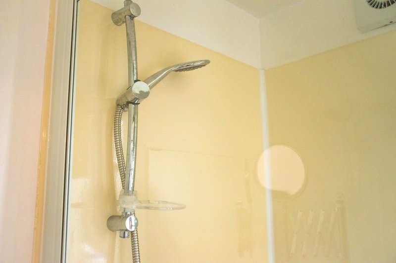 Bathroom shower enclosure with chrome fixtures and glass door panel